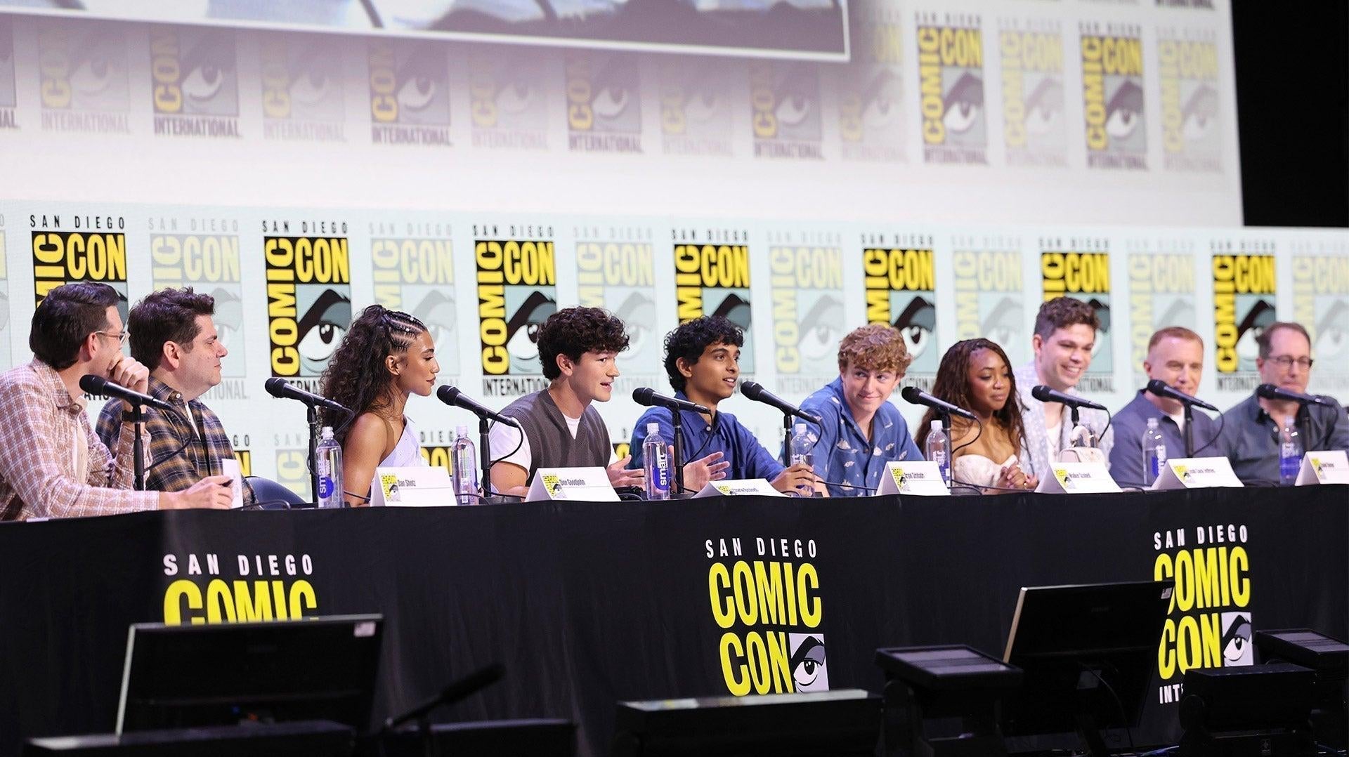Diverse panel of actors and creators at a San Diego Comic-Con event, seated at a long black table.