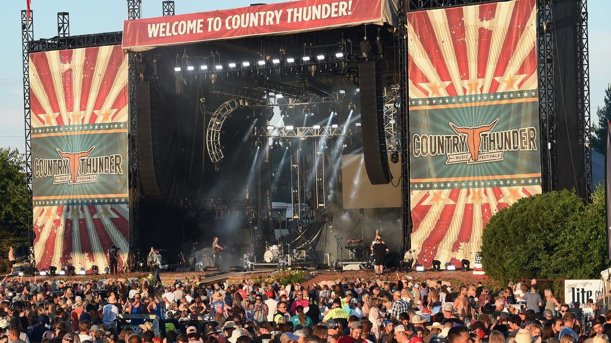 Large outdoor Country Thunder music festival stage with a crowd of attendees.