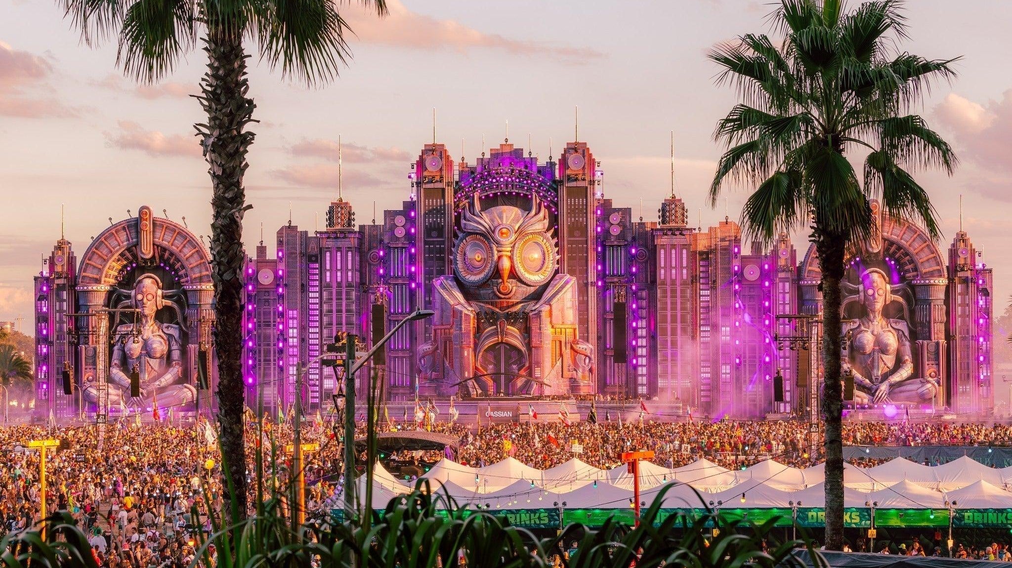 EDC Orlando main stage with a giant owl, purple lights, palm trees, and a massive crowd.