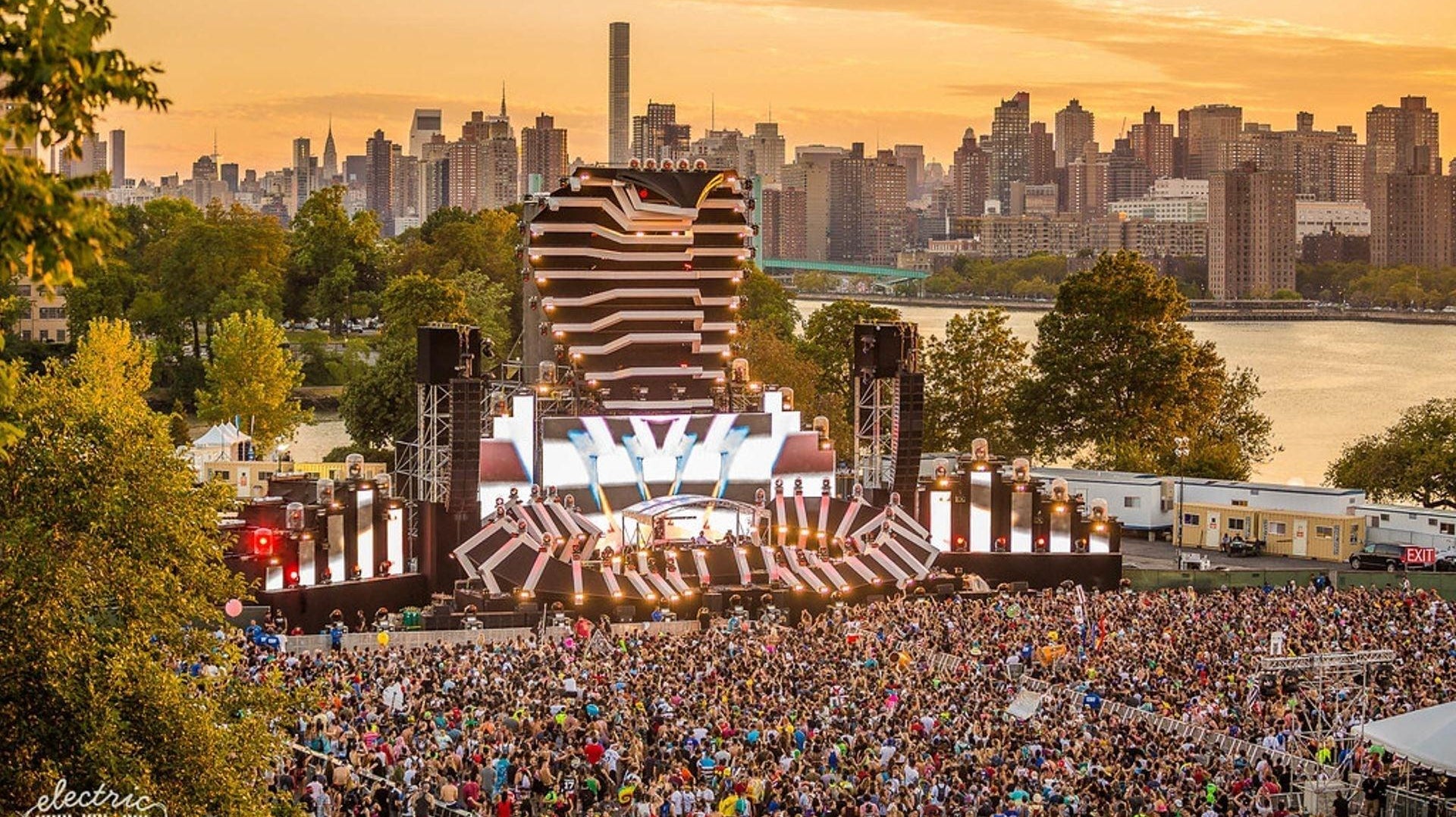 Electric Zoo festival main stage with a large crowd and NYC skyline at sunset.