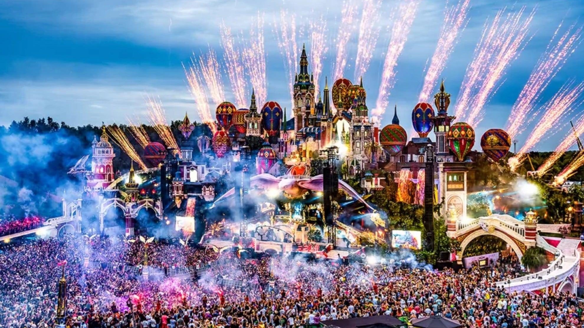 Vibrant Tomorrowland festival main stage with fireworks, colorful lights, and a massive crowd.