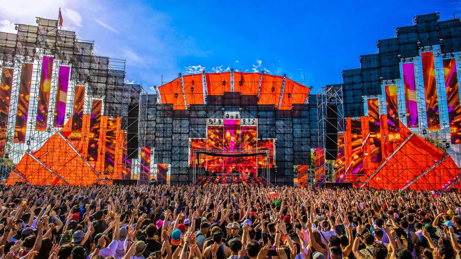 Vibrant festival stage with orange accents and a massive crowd, perfect for November outfit inspiration.