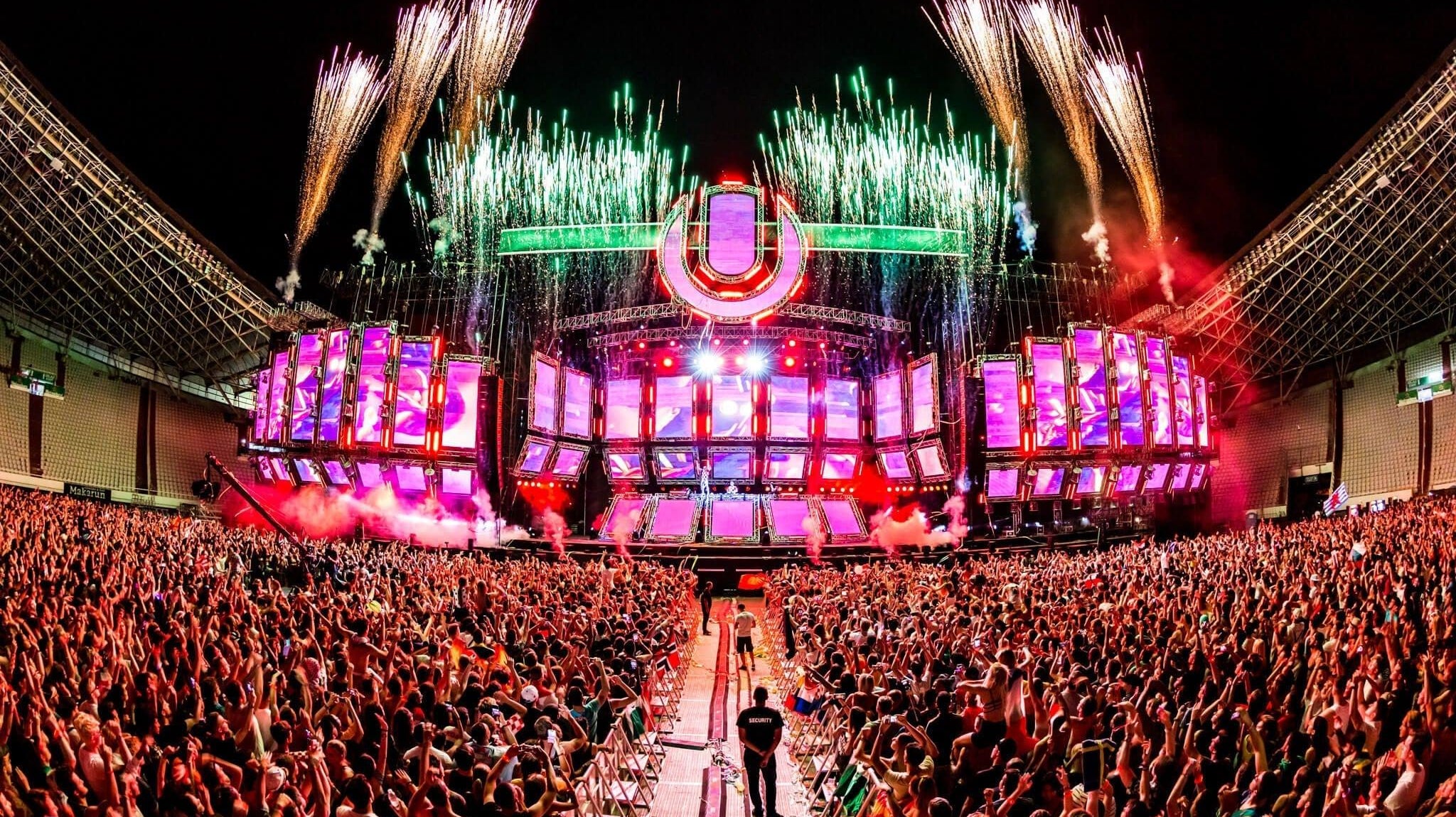 Massive crowd at Ultra Europe festival, fireworks exploding over a vibrant stage with LED screens.