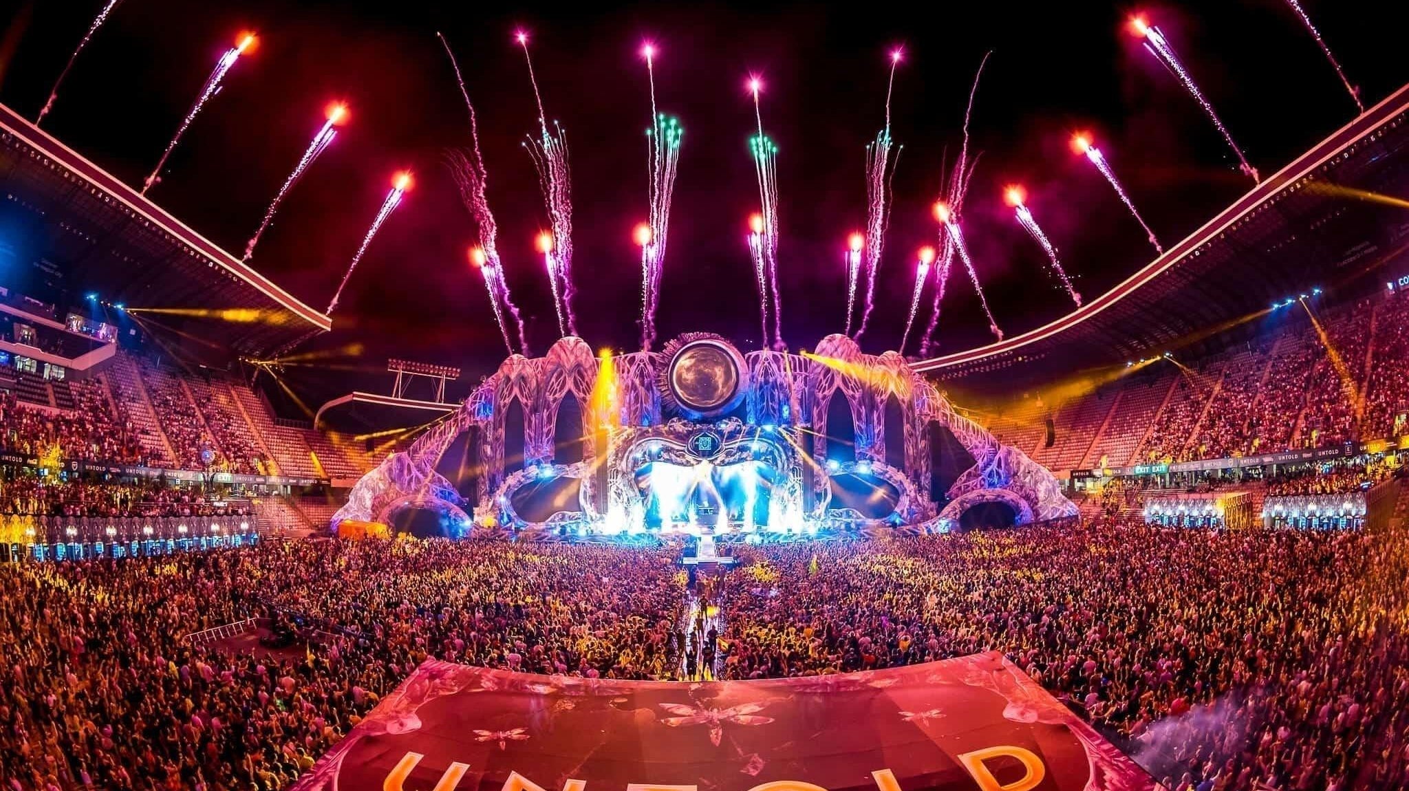 UNTOLD Festival main stage with fireworks, a massive crowd, and a large "UNTOLD" banner.