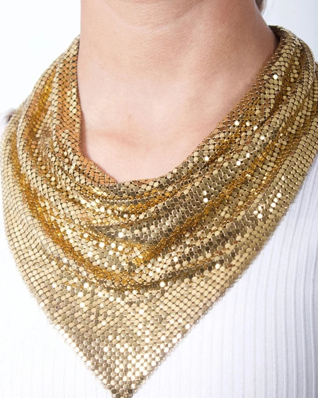 Gold liquid metal mesh scarf with a triangular bib drape, worn over a white top.