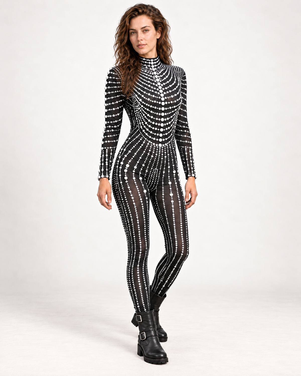Model wearing a black long-sleeve festival jumpsuit adorned with elegant white pearl patterns and a high neckline.