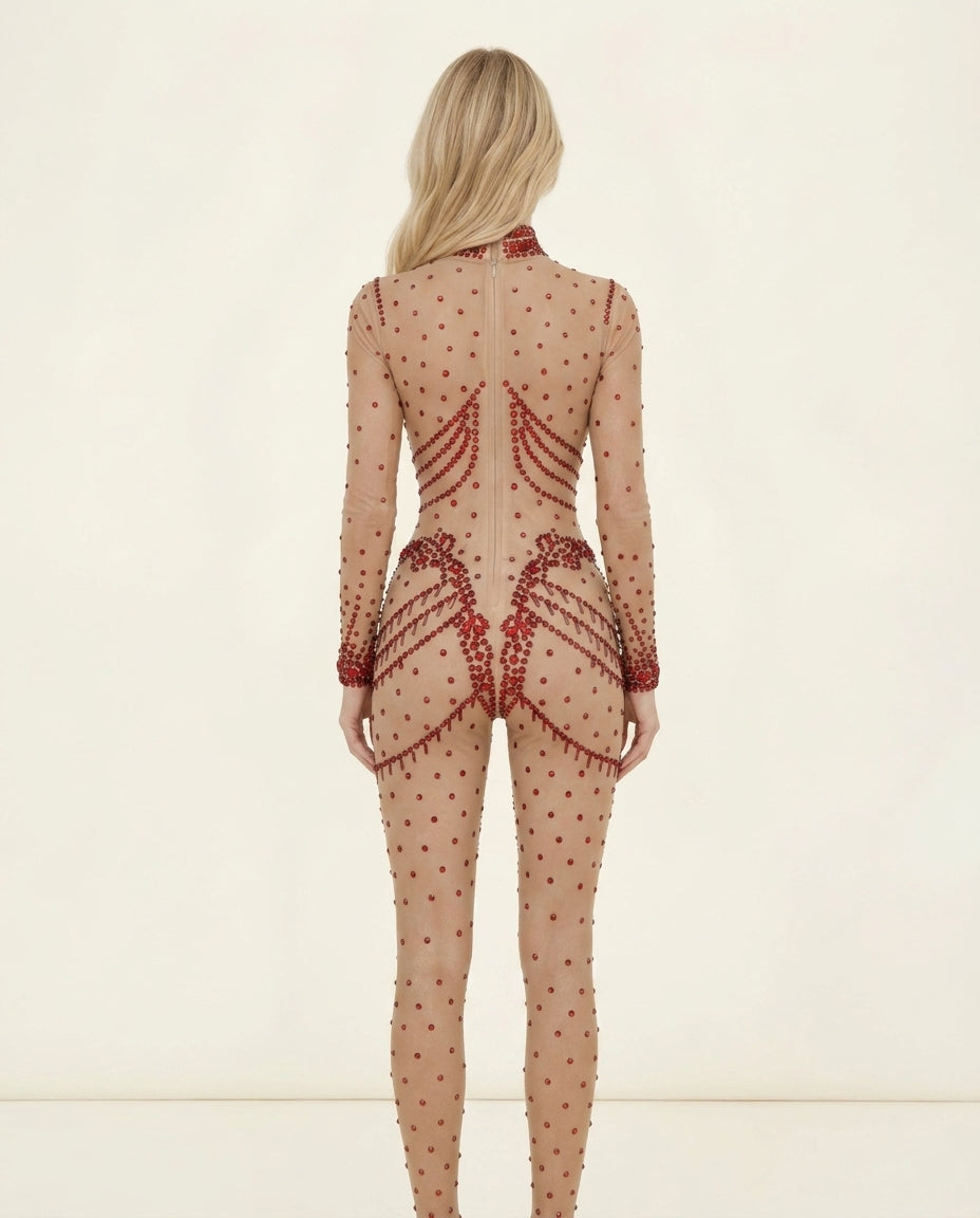 Back view of a blonde woman in a nude Aurora Red Rhinestone Jumpsuit with all-over red embellishments.