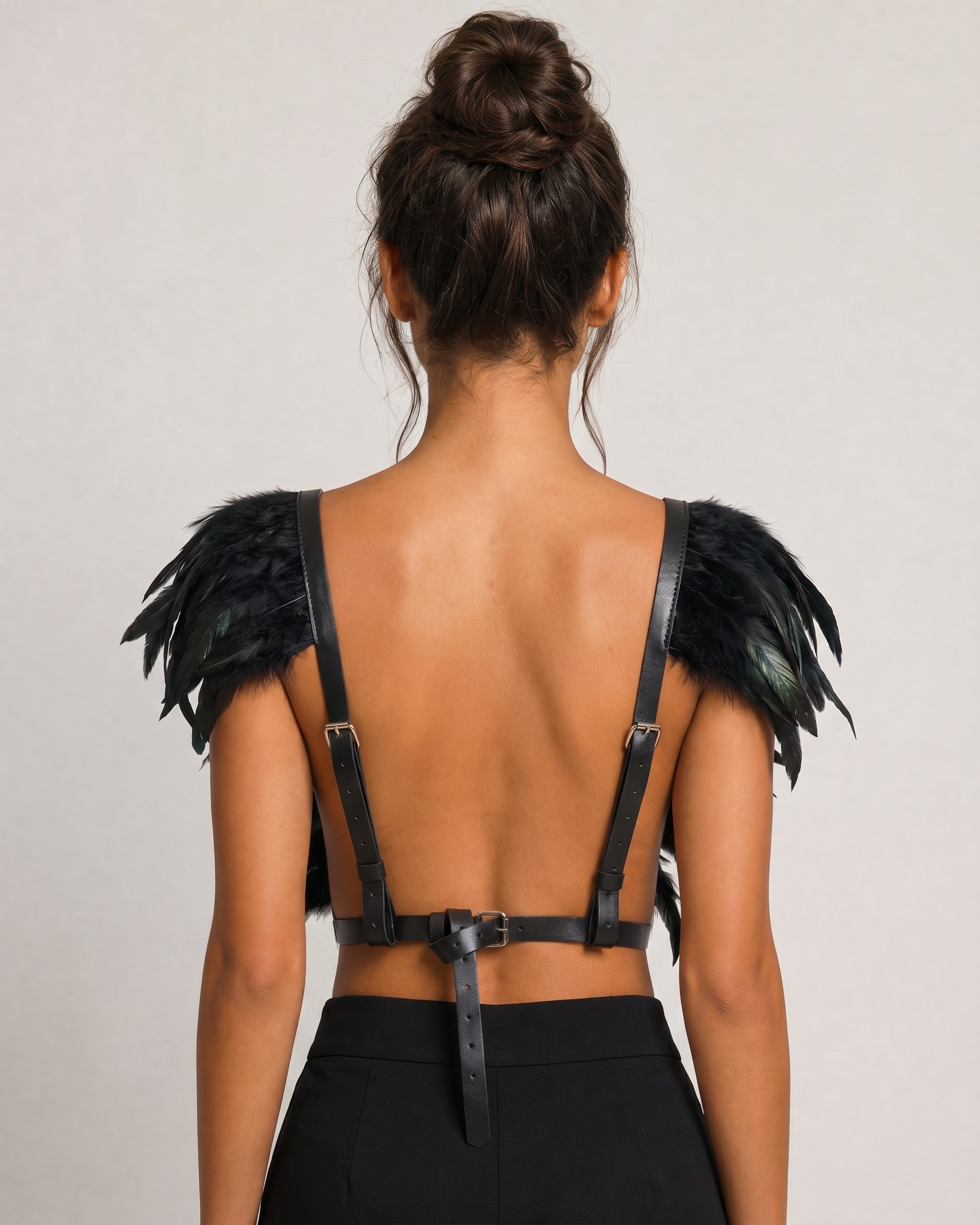 Black feather top with adjustable leather straps and a front button closure, worn on a model's back.
