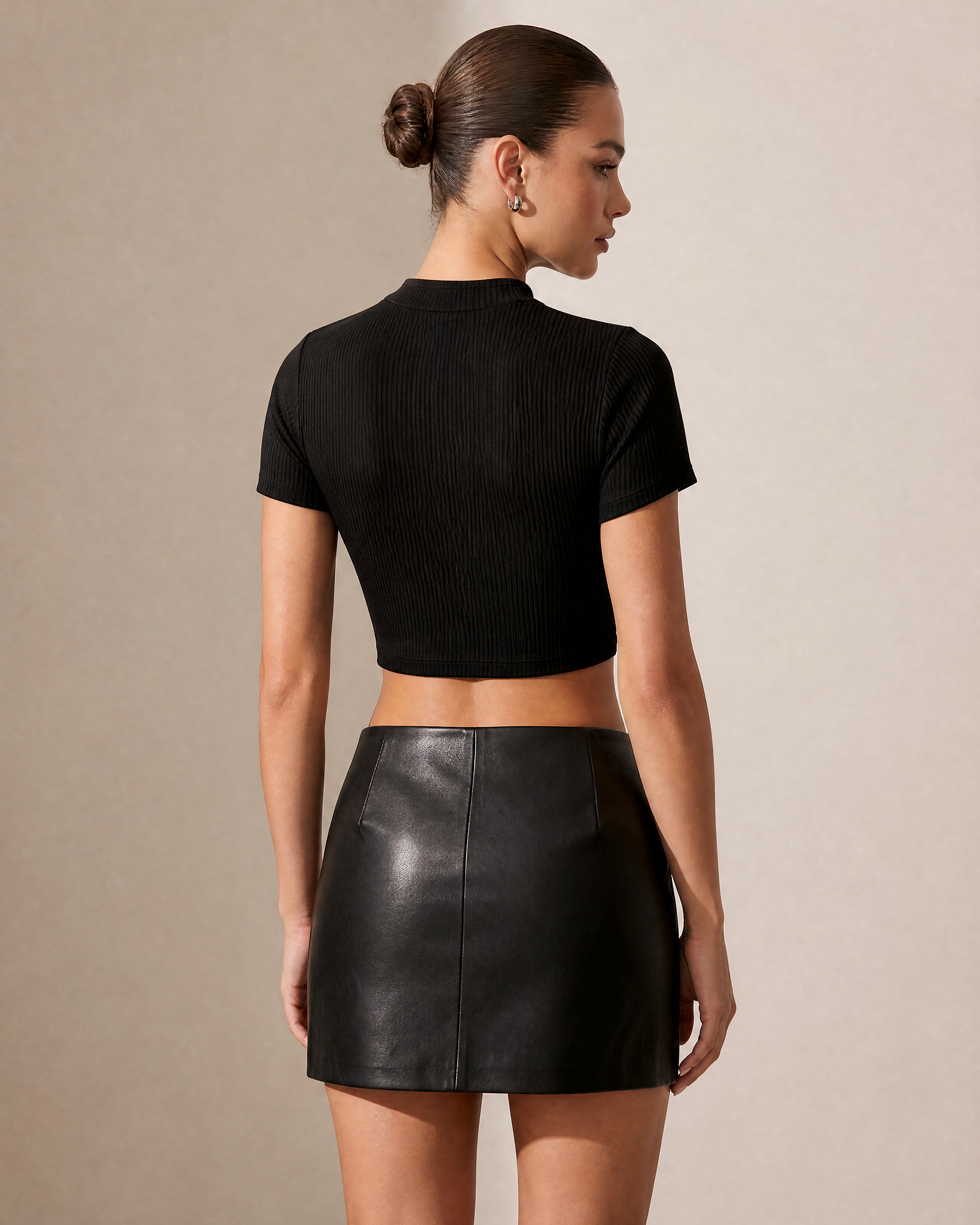 Black ribbed keyhole crop top with short sleeves, paired with a black faux leather mini skirt.