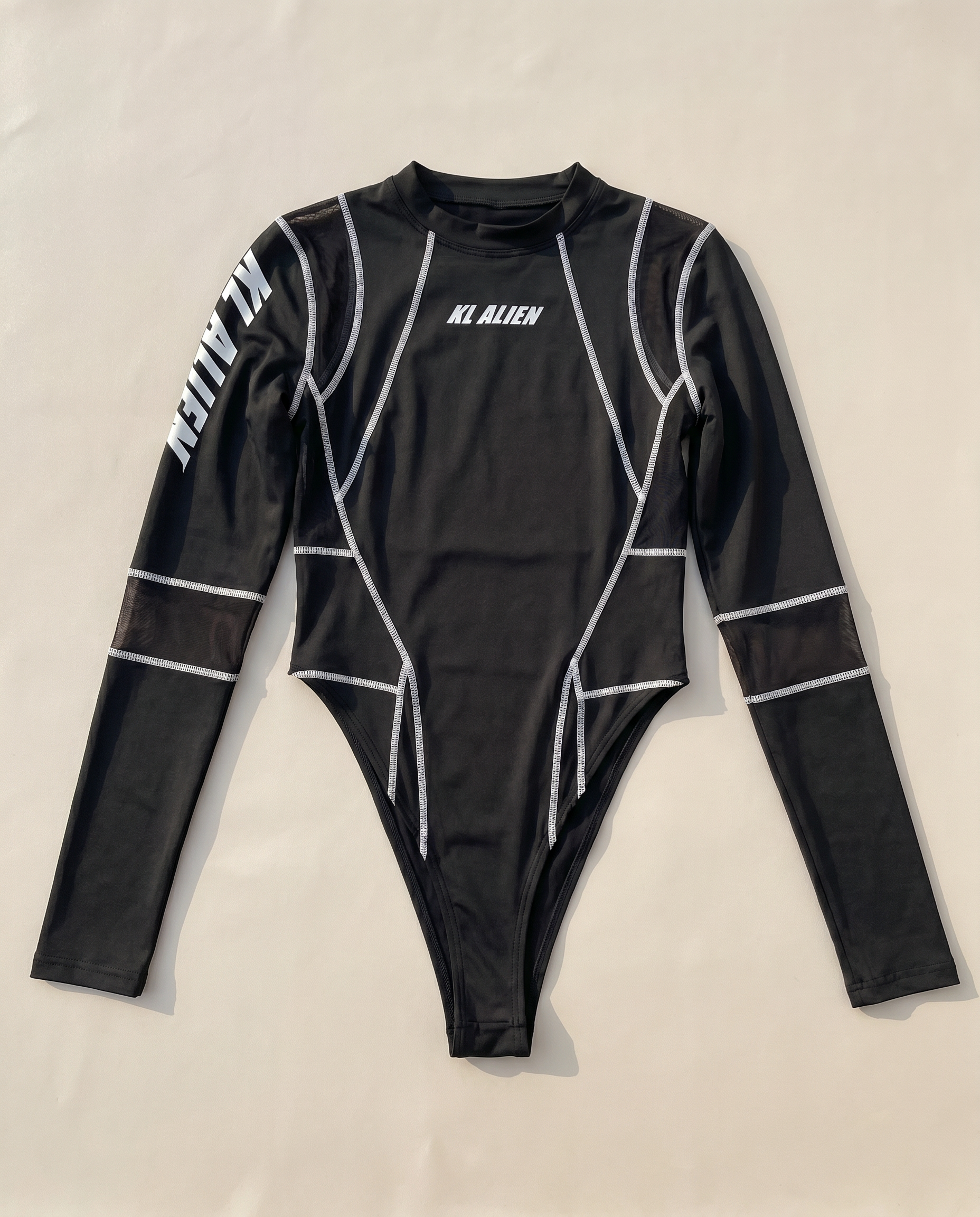 Black long-sleeve rave bodysuit with white "KL ALIEN" text, mesh panels, and white stitching details.
