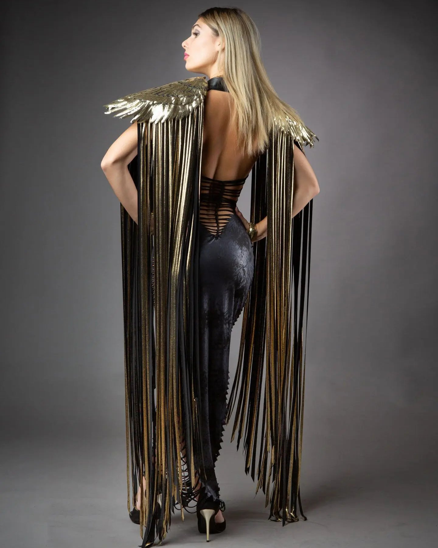 Alas largas de flecos de cosplay que muestran flecos brillantes y acentos dorados en un modelo visto desde atrás.