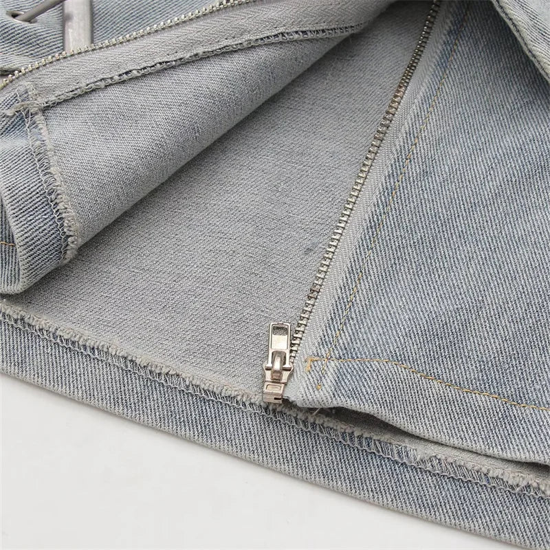 Primer plano del detalle de la cremallera de la Minifalda de Mezclilla con Cinturón Cruzado, mostrando la tela de mezclilla de calidad.