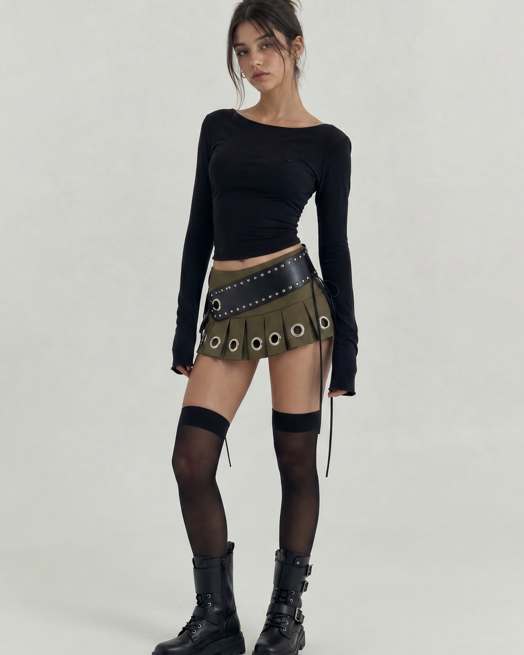 Green pleated mini skirt with large silver grommets and a wide black studded belt.