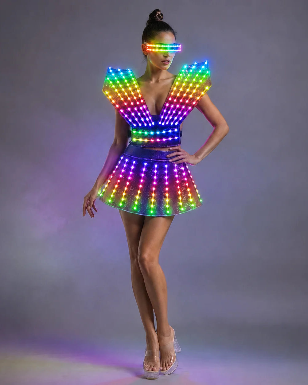 Model wearing a futuristic LED dress with rainbow glowing lights, structured shoulders, and matching light-up visor.