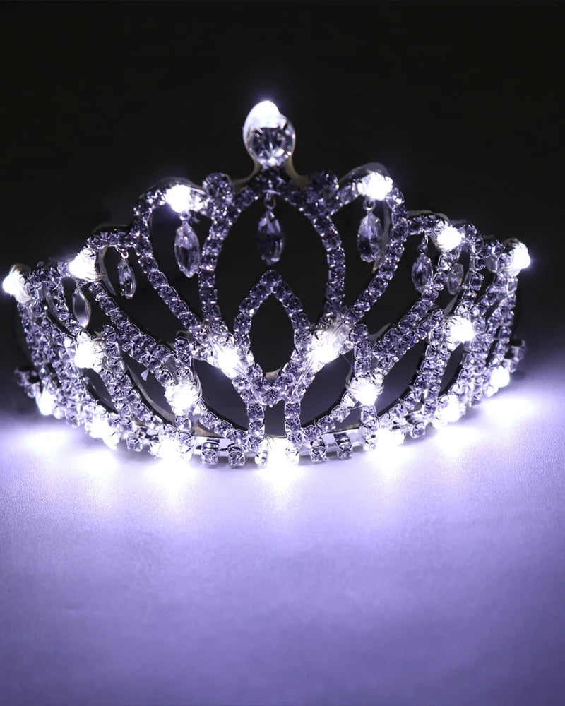 Glowing rhinestone tiara featuring intricate silver filigree and bright white LED lights against a dark background.