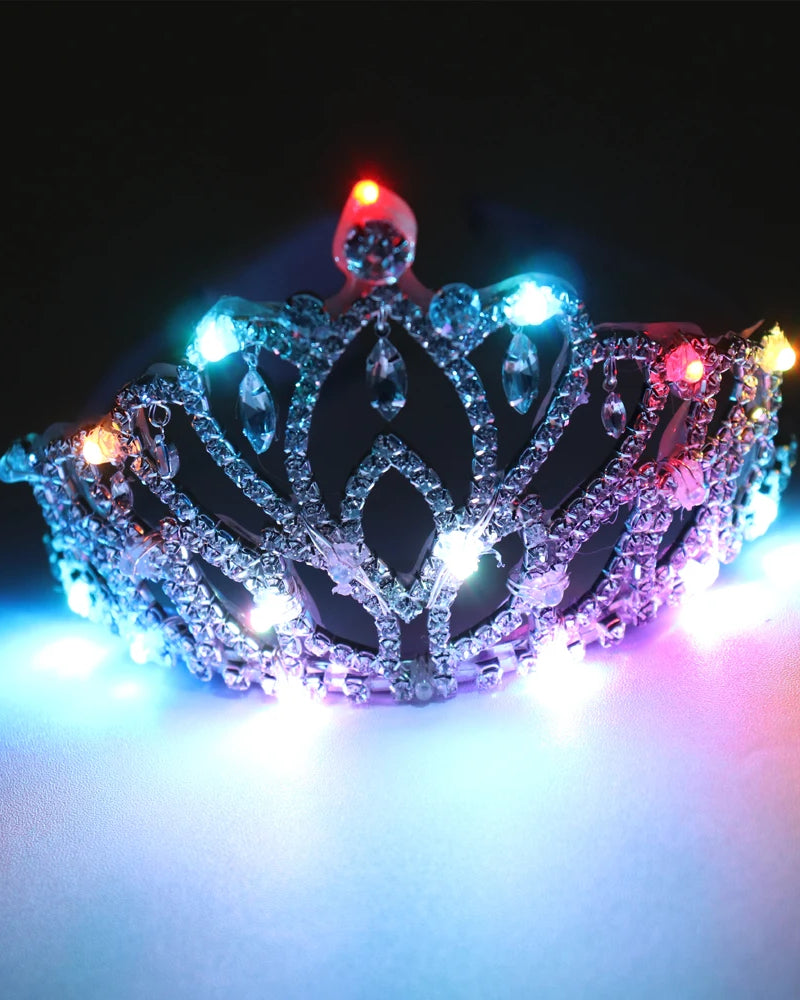Silver rhinestone tiara featuring intricate filigree patterns and glowing multicolored LED lights against a dark background.