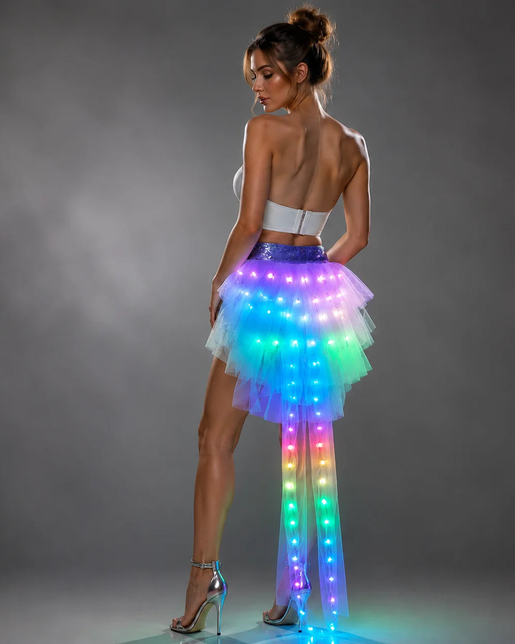 Model wearing a layered tulle LED tutu skirt with multi-colored glowing lights and a sparkling purple waistband.
