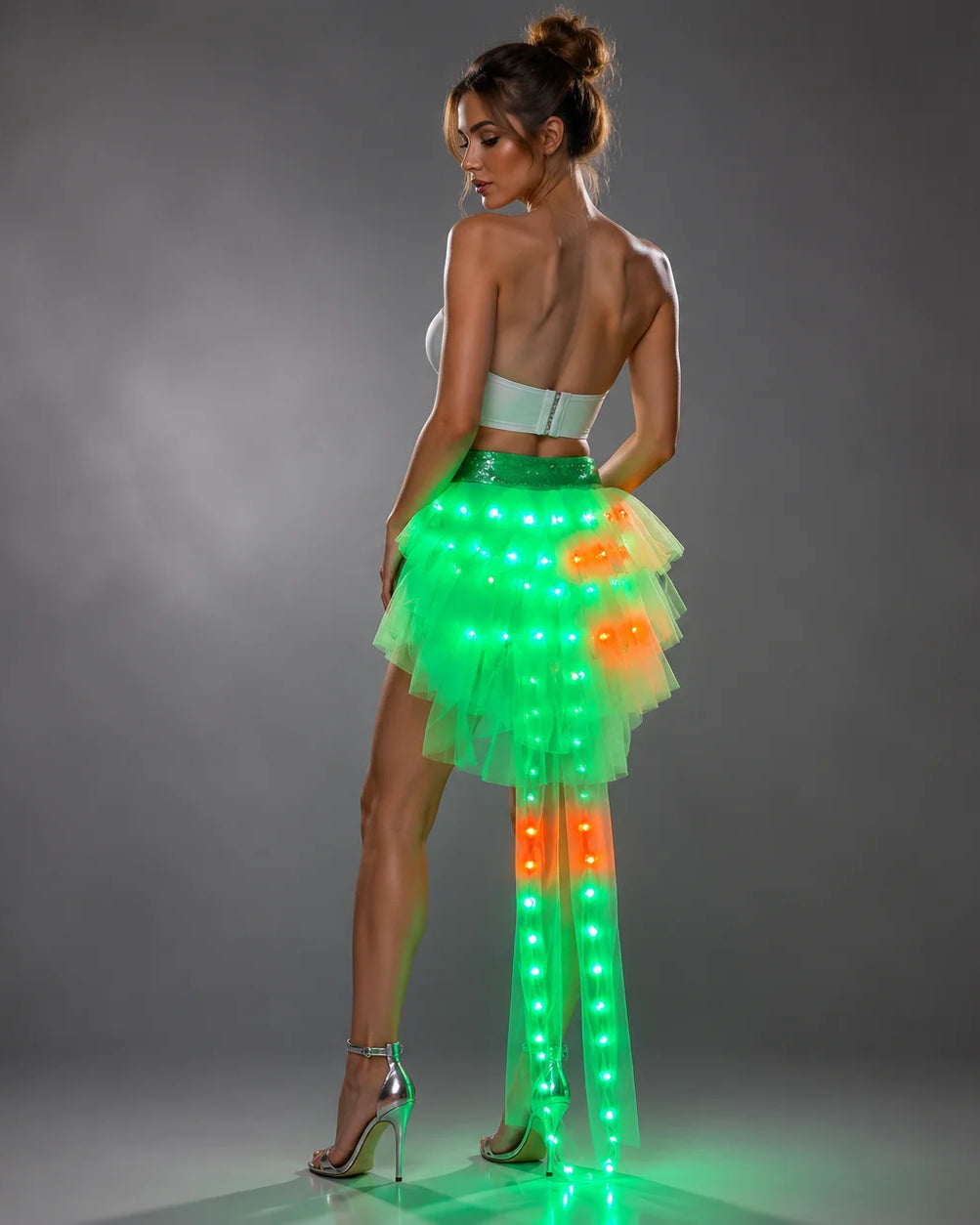 Model wearing a layered tulle LED tutu skirt featuring glowing green and orange lights with a remote-controlled design.