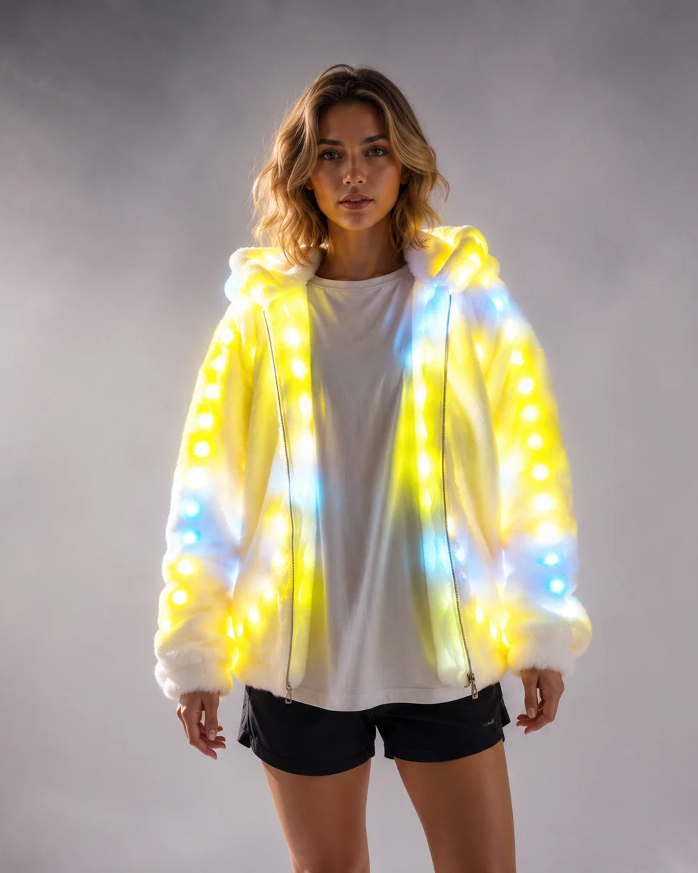 Model wearing a white faux fur hooded jacket featuring integrated, glowing yellow and blue LED lights.