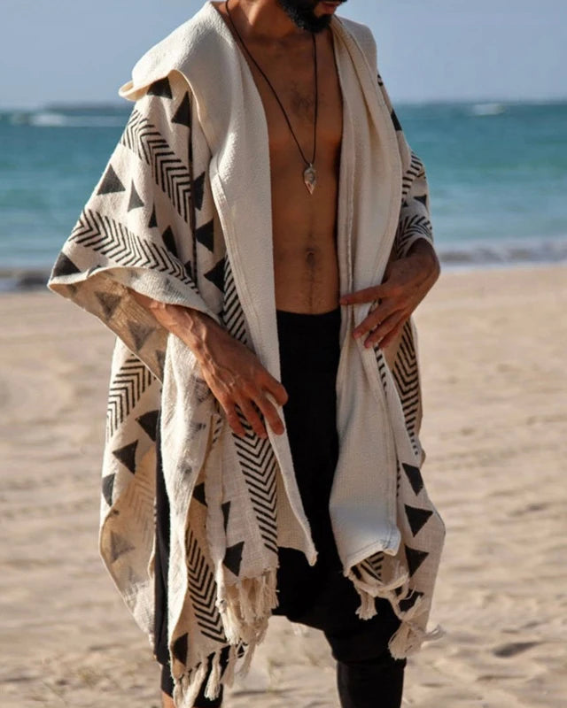 Men's Tulum Fringe Cardigan: beige polyester with black geometric patterns and fringe hem, worn open on a beach.