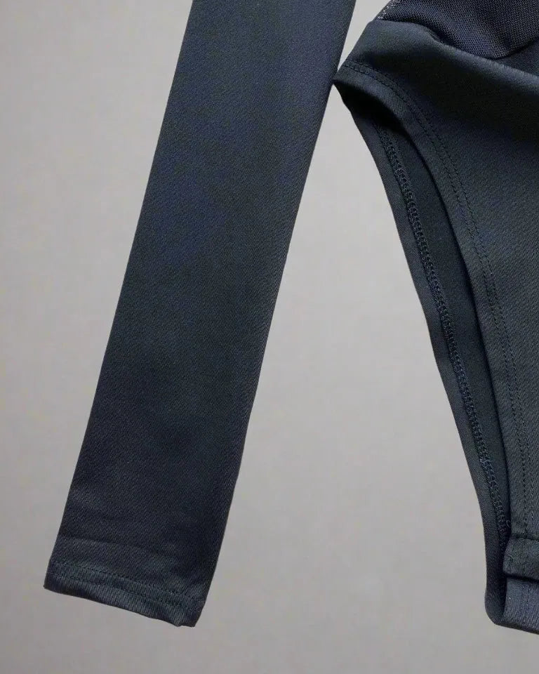 Gros plan sur la manche et le détail du tissu du Body en patchwork en maille, mettant en valeur son matériau léger.