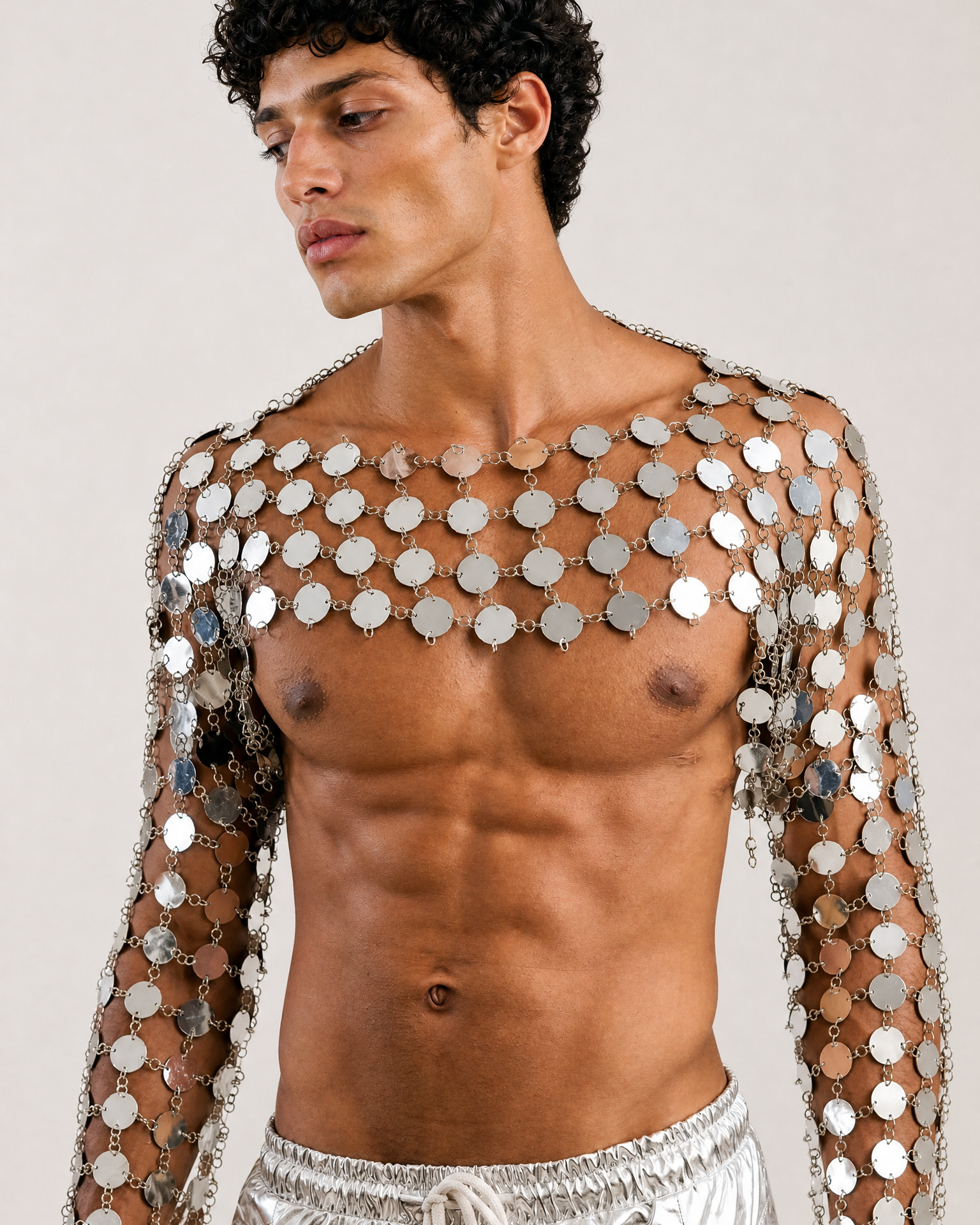 Silver metal chain crop top featuring interconnected circular discs in an armor-inspired design with long sleeves.