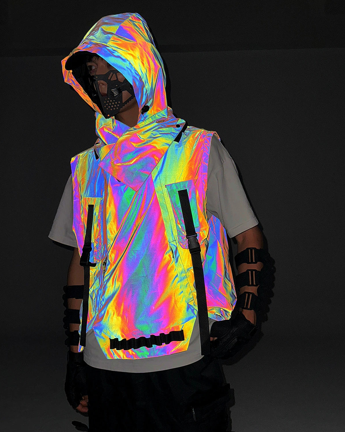 Multicolor reflective techno vest with hood, worn over a white tee, showcasing its iridescent glow in darkness.