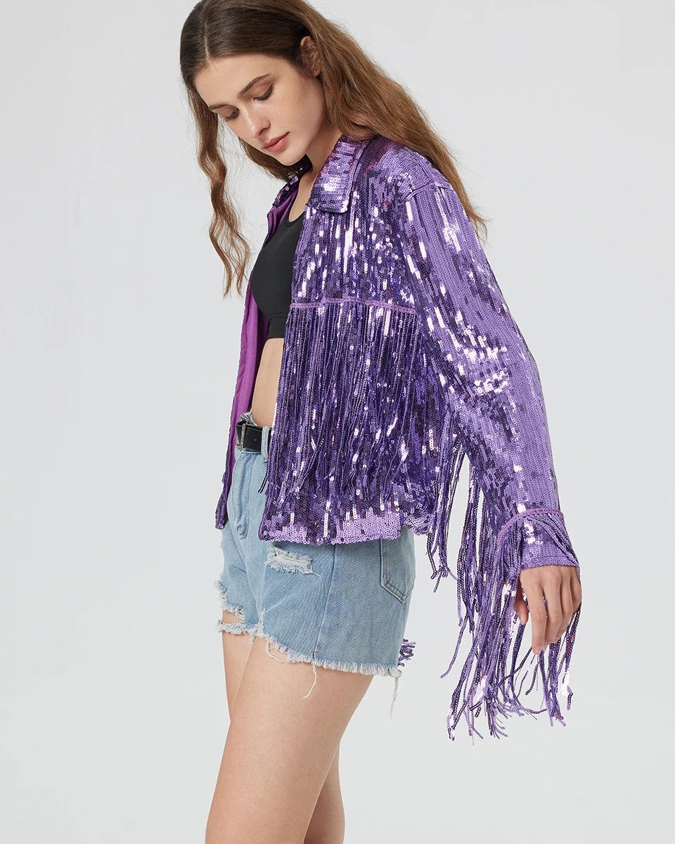 Purple metallic sequin jacket with long fringe sleeves worn over a black top and denim shorts.