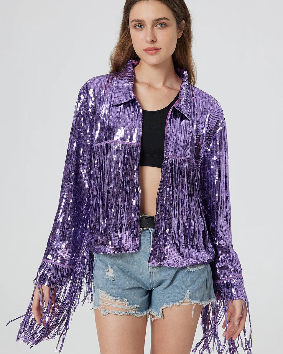 Purple metallic sequin jacket featuring long fringe trim on the sleeves and bodice, worn over a black top and denim shorts.