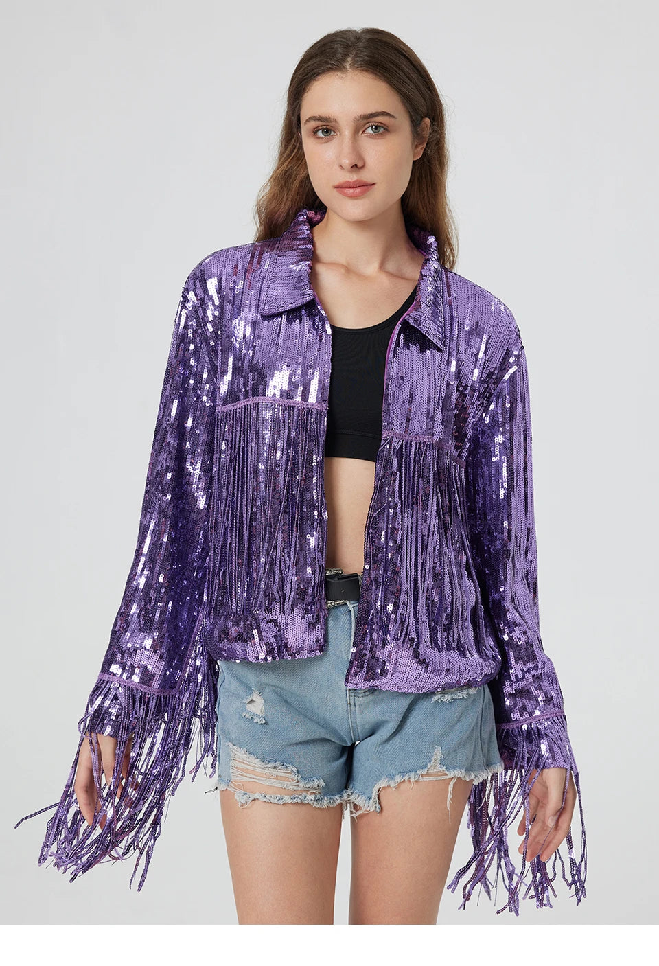 Purple metallic sequin jacket featuring long fringe trim on the sleeves and bodice, worn over a black top and denim shorts.