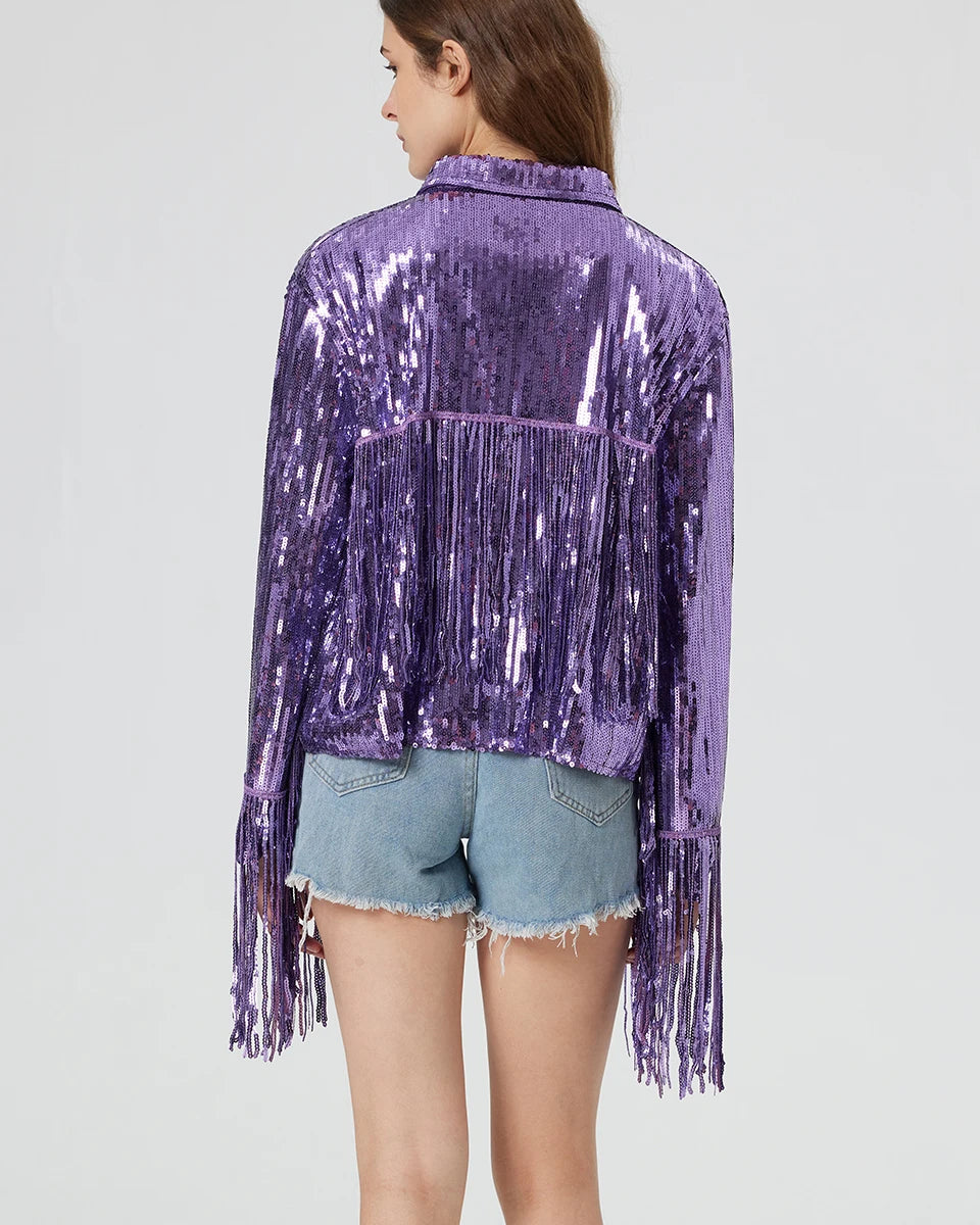Purple metallic sequin jacket with long fringe detailing on the back and sleeves, worn over denim shorts.