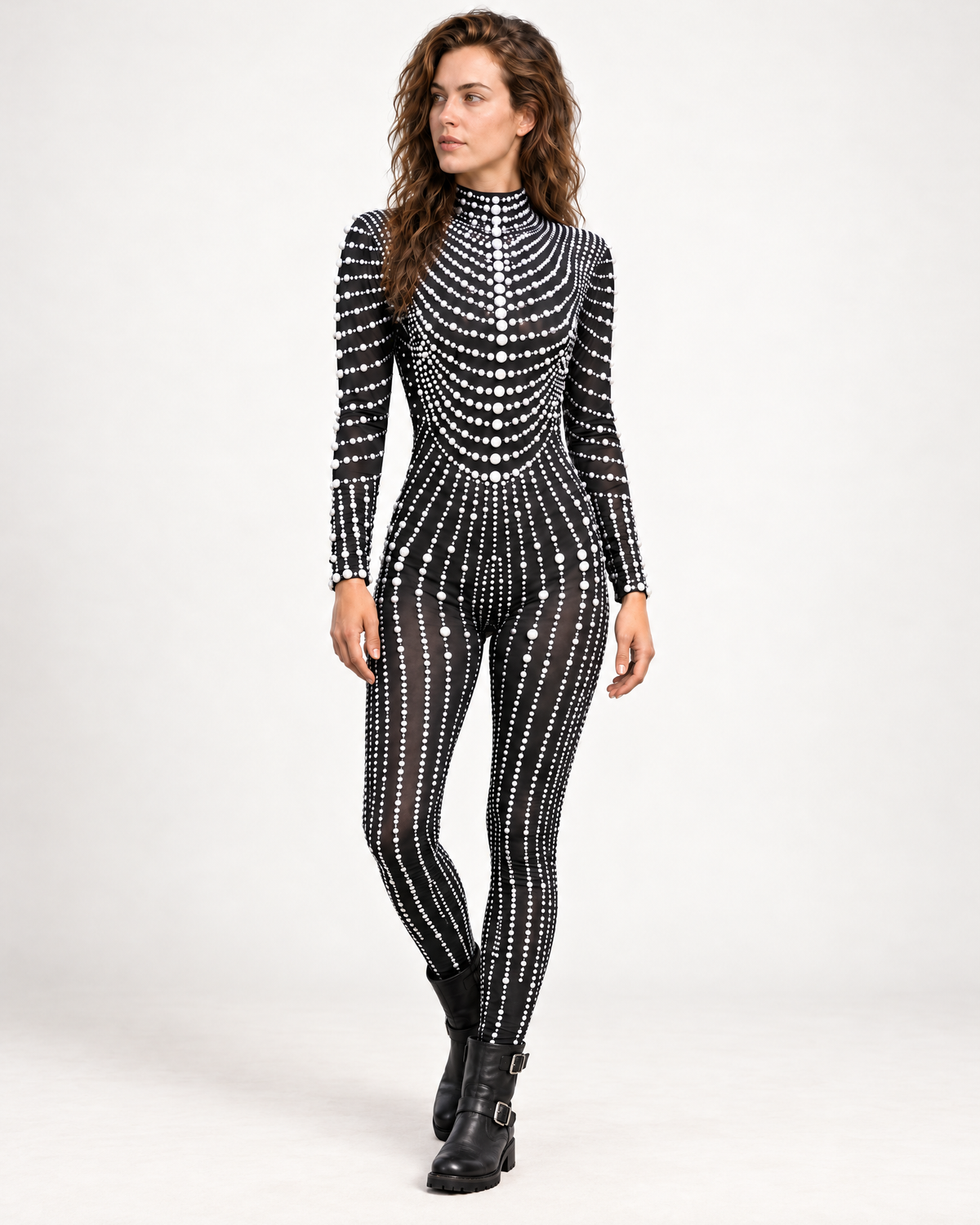 Model wearing a black long-sleeve jumpsuit adorned with intricate white pearl patterns and a high neckline.