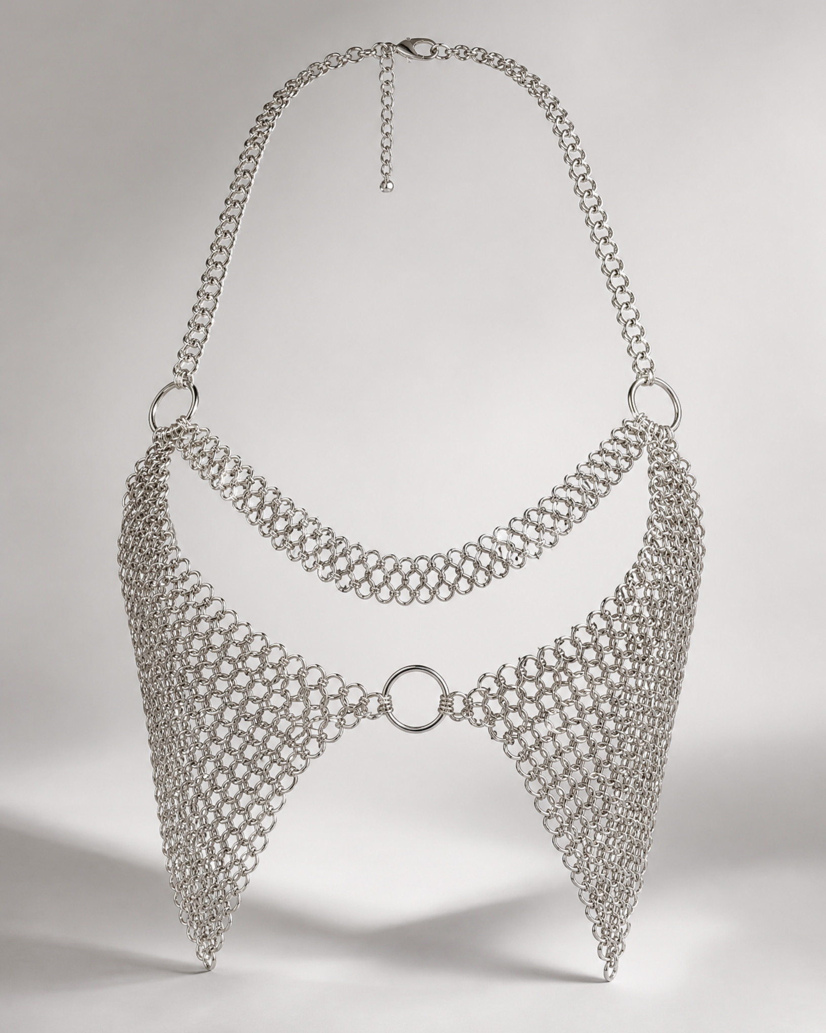 Silver chainmail-style bralette with halter neck, central ring, and adjustable clasp.