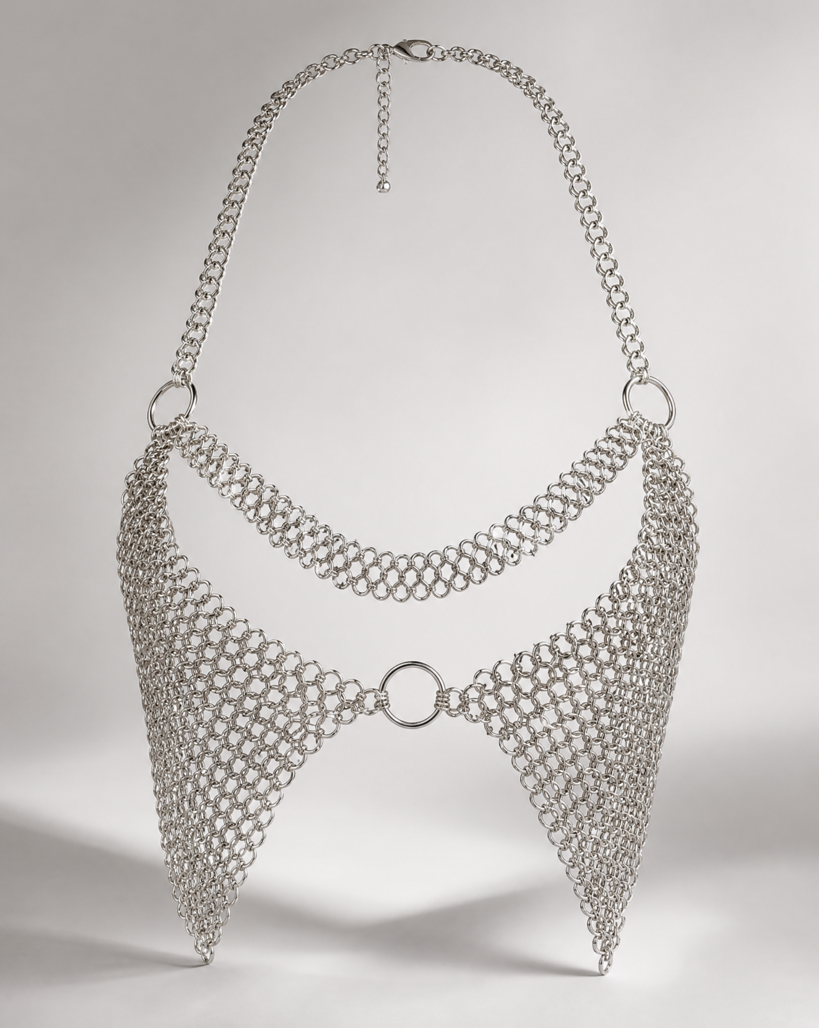 Silver chainmail-style bralette with halter neck, central ring, and adjustable clasp.