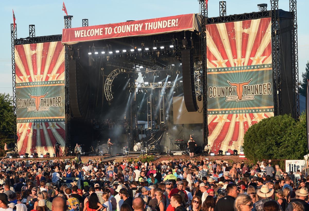 Large outdoor Country Thunder music festival stage with a crowd of attendees.