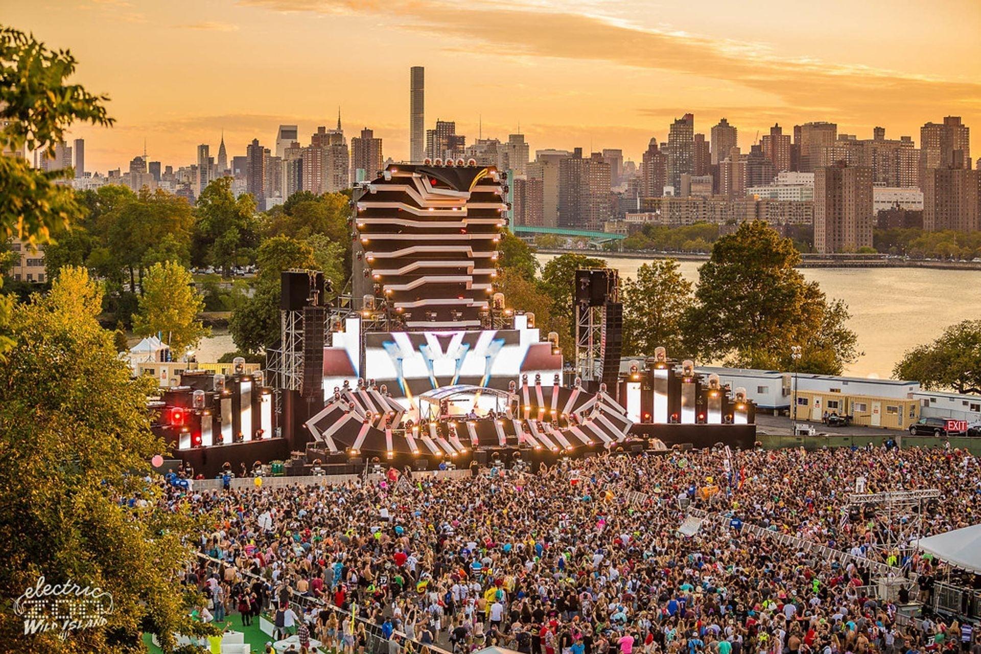 Electric Zoo festival main stage with a large crowd and NYC skyline at sunset.