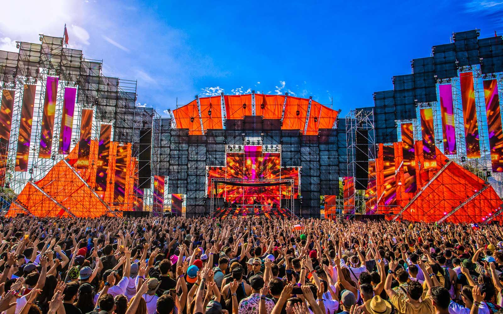Vibrant festival stage with orange accents and a massive crowd, perfect for November outfit inspiration.