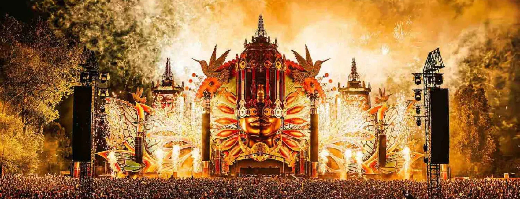 Mysteryland festival main stage with intricate golden bird and face designs, fireworks, and a massive crowd.