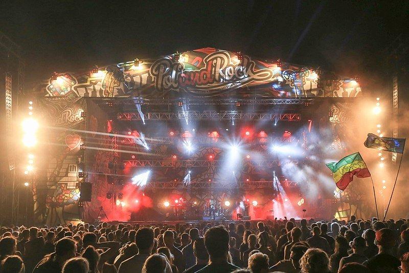 Crowd enjoying a vibrant rock festival stage with bright lights and "Pol'and'Rock" signage.
