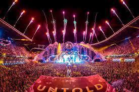 Vibrant Untold Festival stage with fireworks, a massive crowd, and dazzling lights at night.