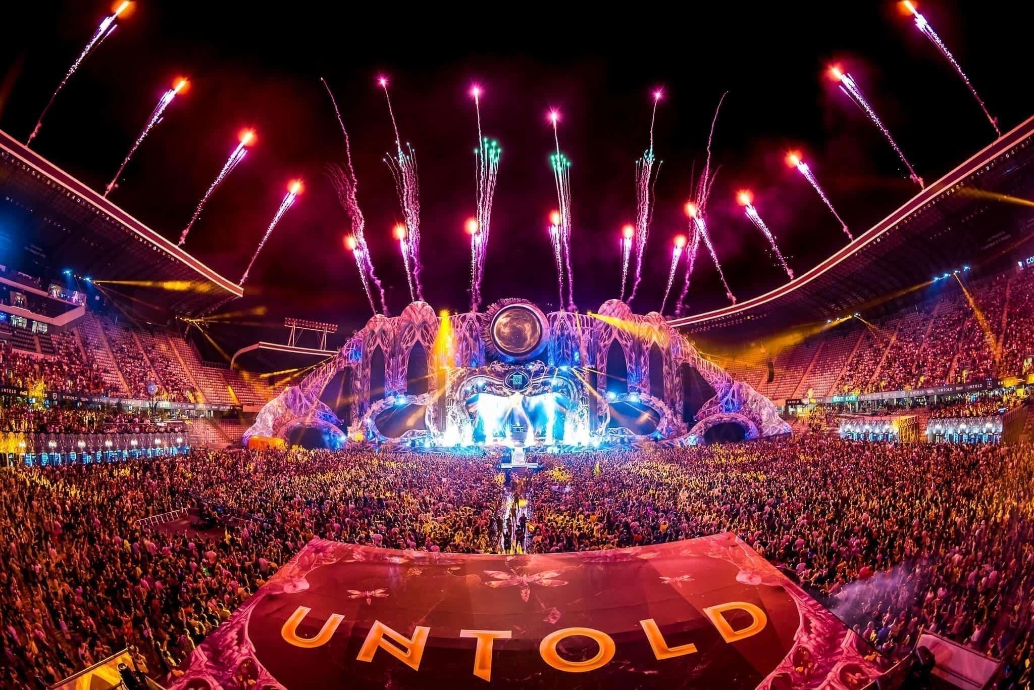 UNTOLD Festival main stage with fireworks, a massive crowd, and a large "UNTOLD" banner.
