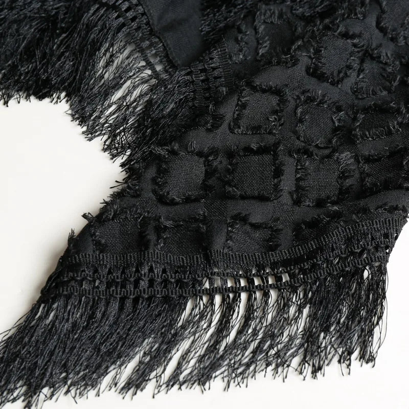 Close-up of a black Lucian Boho Fringe Vest, showing textured fabric and dramatic fringe tassels.