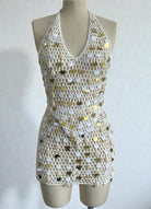 Mannequin wearing a patterned dress with gold and white polka dots on a plain background