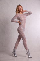 Model wearing a long-sleeve, sheer-look jumpsuit covered in intricate hand-glued rhinestones with a sculpting fit.