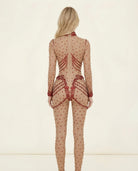 Back view of a blonde woman in a nude Aurora Red Rhinestone Jumpsuit with all-over red embellishments.