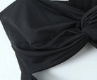 Haut froncé dos nu en tissu noir mettant en valeur un design froncé élégant et un détail sexy dos nu.