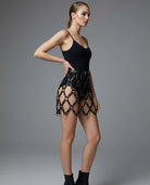 Black faux leather grid mini skirt with daring cutouts and silver O-rings worn by a model.