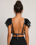 Black feather top with adjustable leather straps and a front button closure, worn on a model's back.