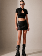 Black ribbed keyhole crop top with short sleeves, paired with a black leather skirt and boots.