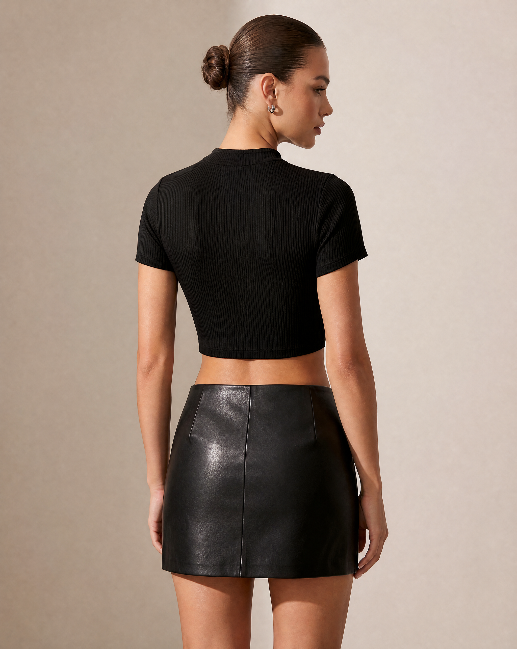Black ribbed keyhole crop top with short sleeves, paired with a black faux leather mini skirt.